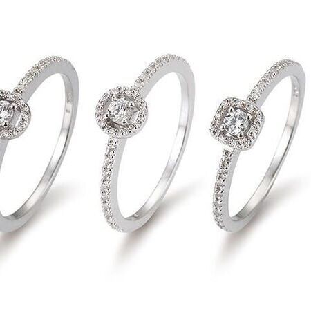 Drei diamantbesetzte, silberne Verlobungsringe auf weißem Hintergrund